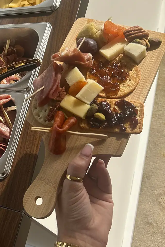 A guest holds a board of cured meats, cheese and jam beside the stainless bins